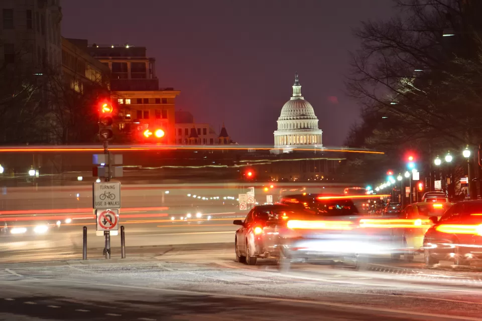 View of U.S capitol dome at night with blurred traffic in foreground